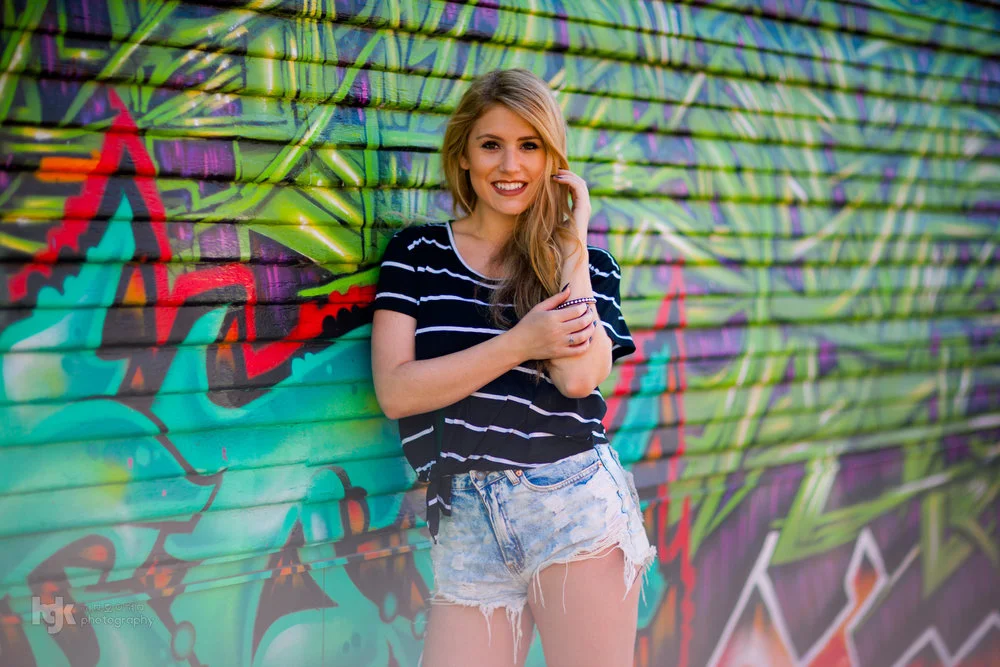 Model standing before a vivid multicolored graffiti wall.