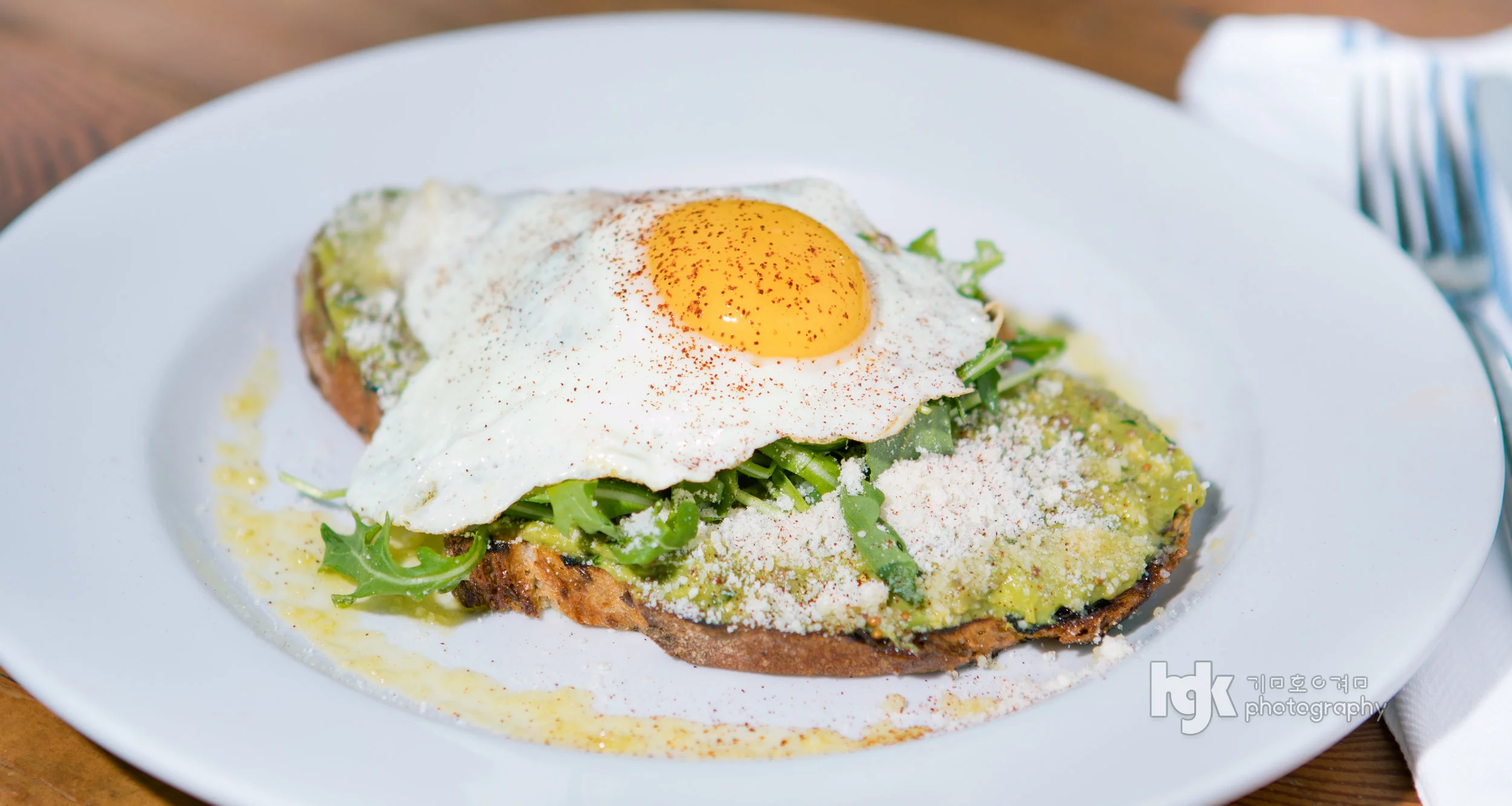 Open-faced toast topped with a fried egg, greens and grated cheese.