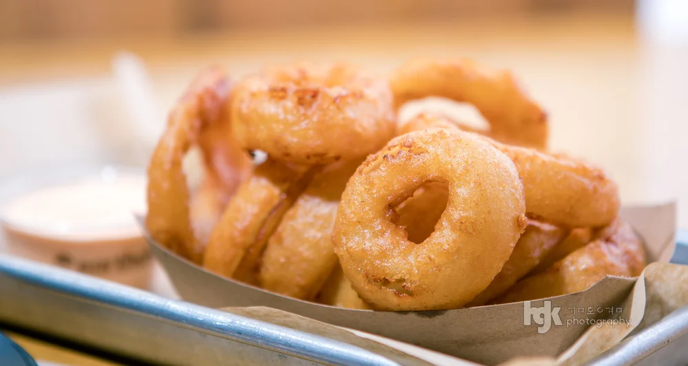 Basket of golden onion rings photographed in close-up.