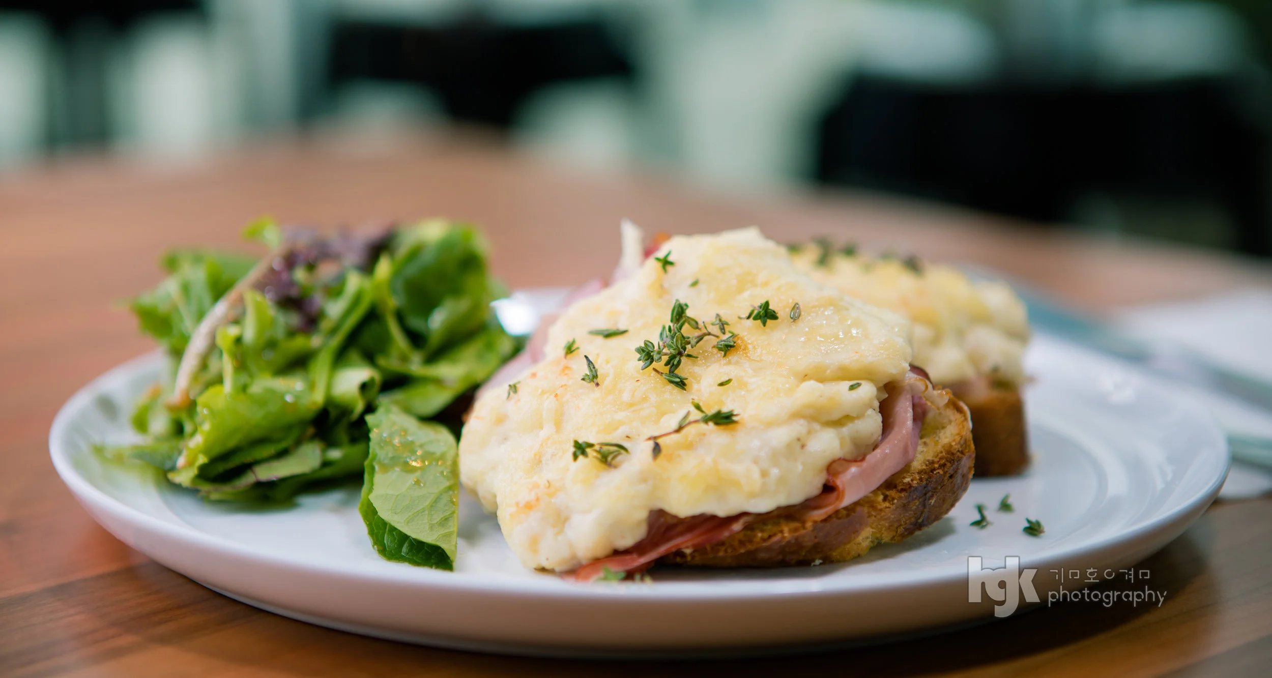 Open-faced breakfast sandwich topped with melted cheese and served with a green salad.