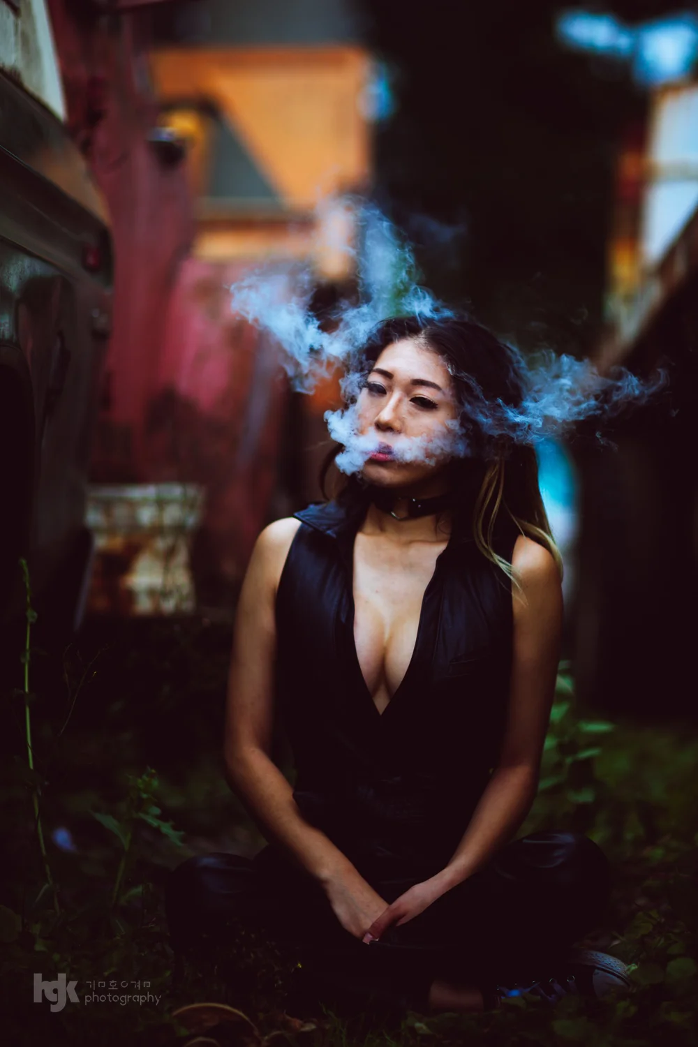Model exhaling a cloud of smoke in a dark editorial portrait.
