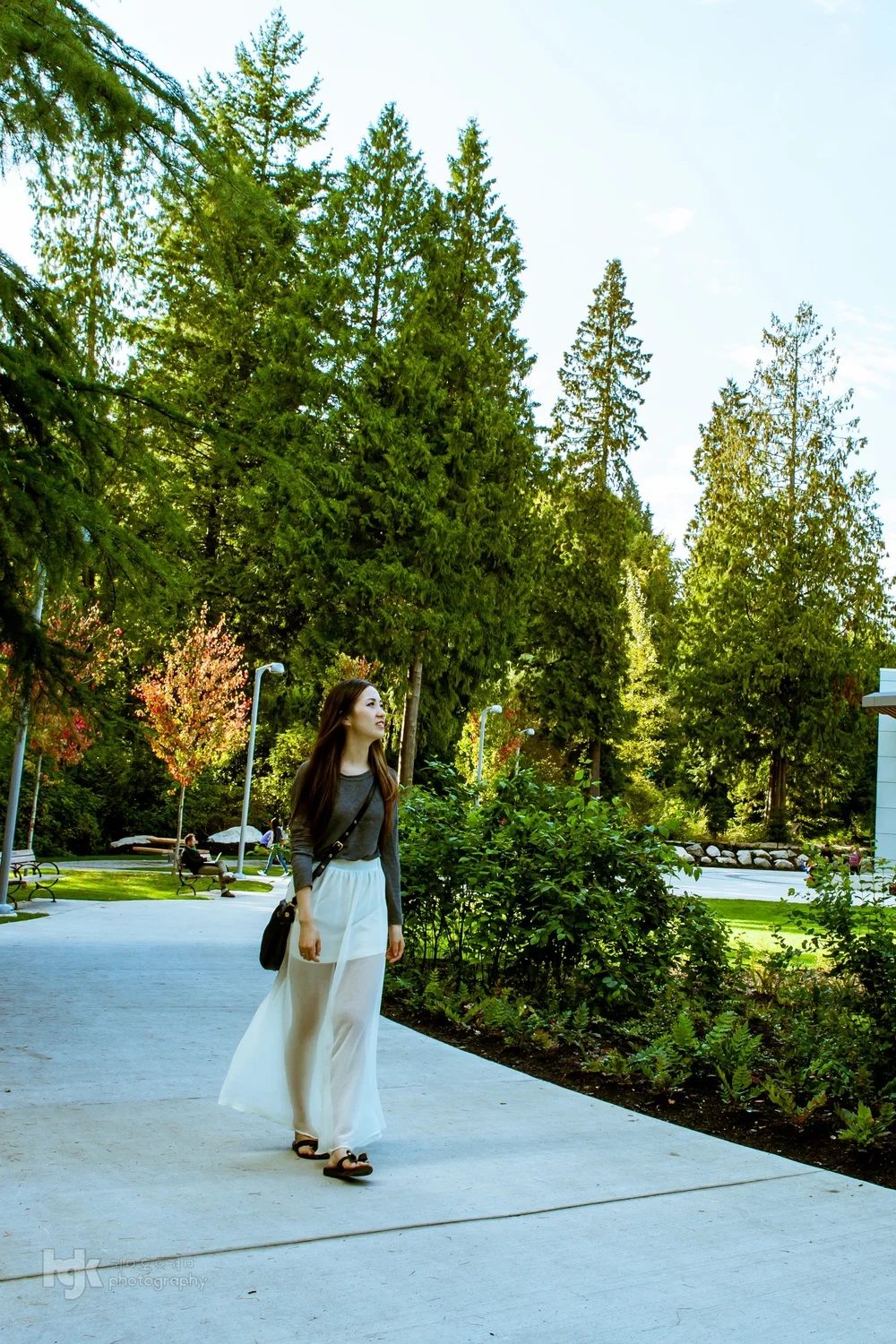 Model standing among dense greenery in a landscaped Vancouver garden.