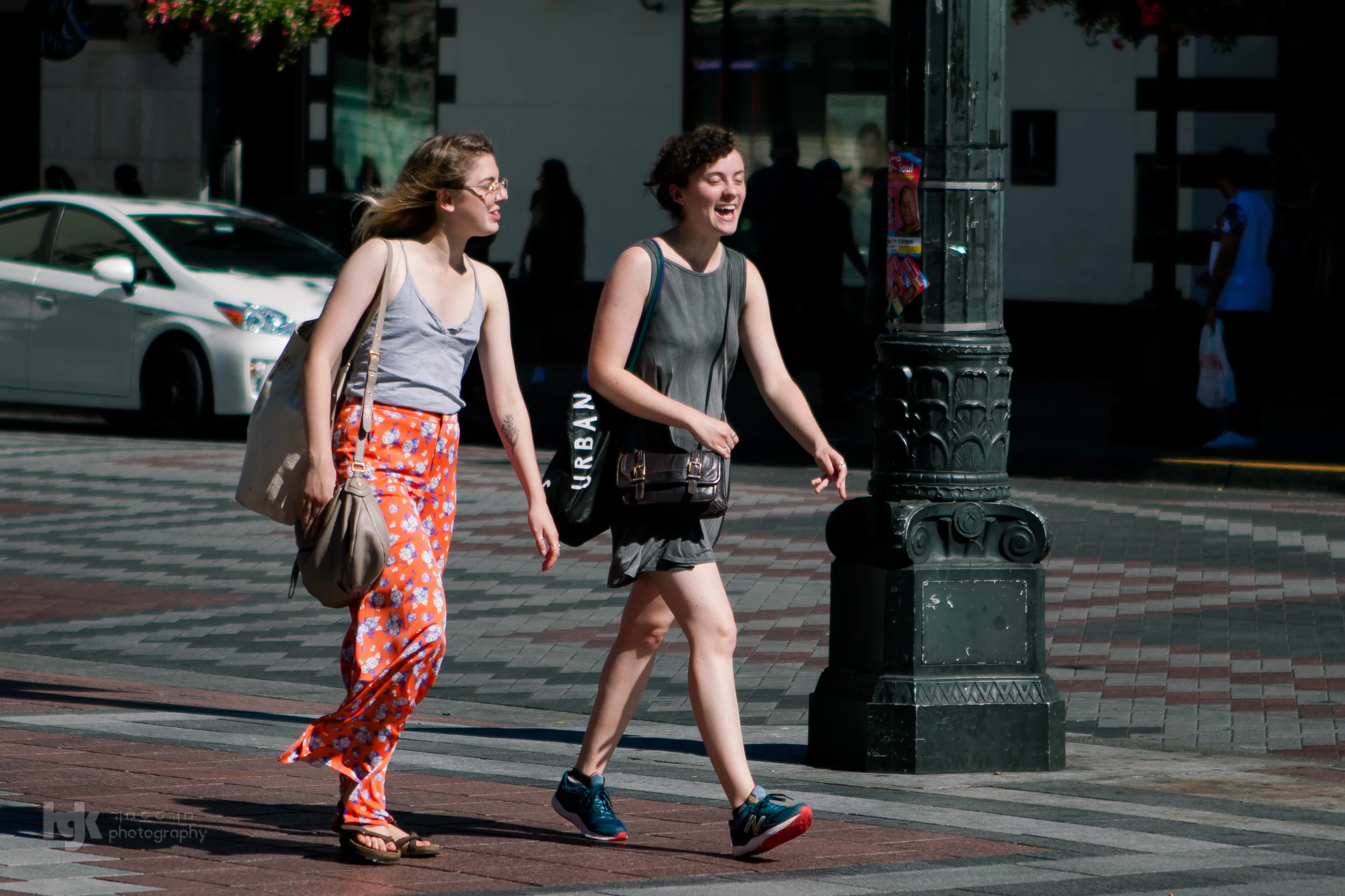 Two pedestrians laughing as they cross a city street.